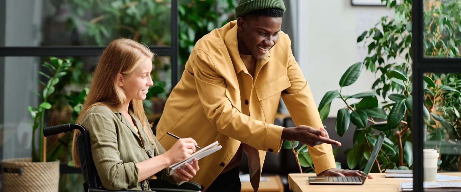 Young confident businessman pointing at laptop screen during presentation of project points to colleague making notes